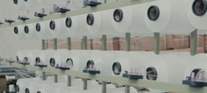 Rows of white polyester yarn spools ready for lanyard production